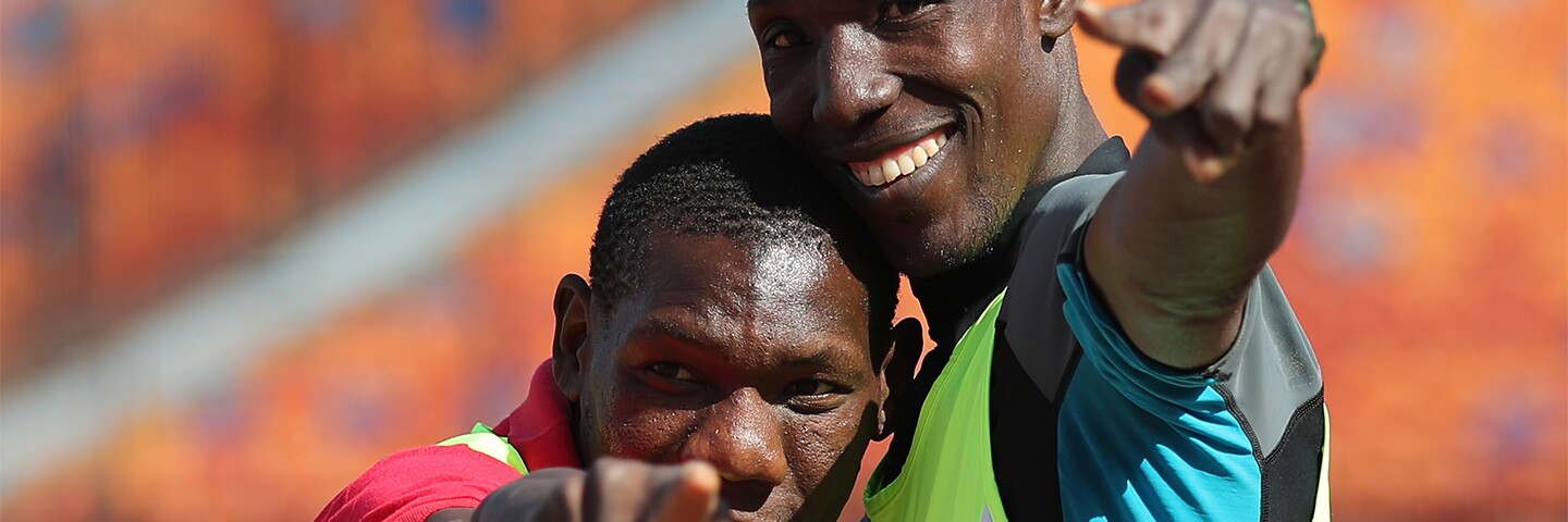 two athletes hugging and giving a peace sign. 