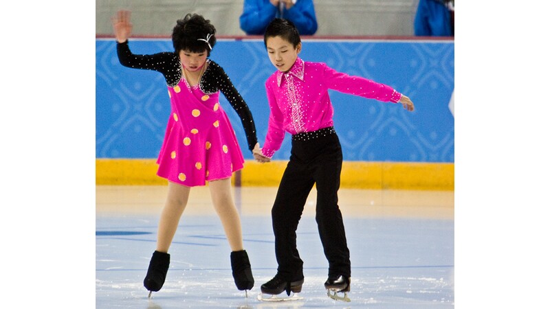 A young male and female skater on the ice. 