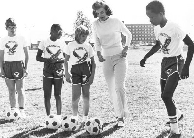 Eunice and athletes kicking footballs. 