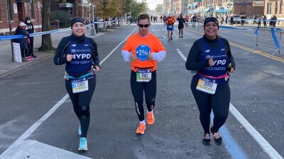 Special Olympics athlete, Chris Nikic, runs alongside two New York Police Department women in the NYC marathon. 