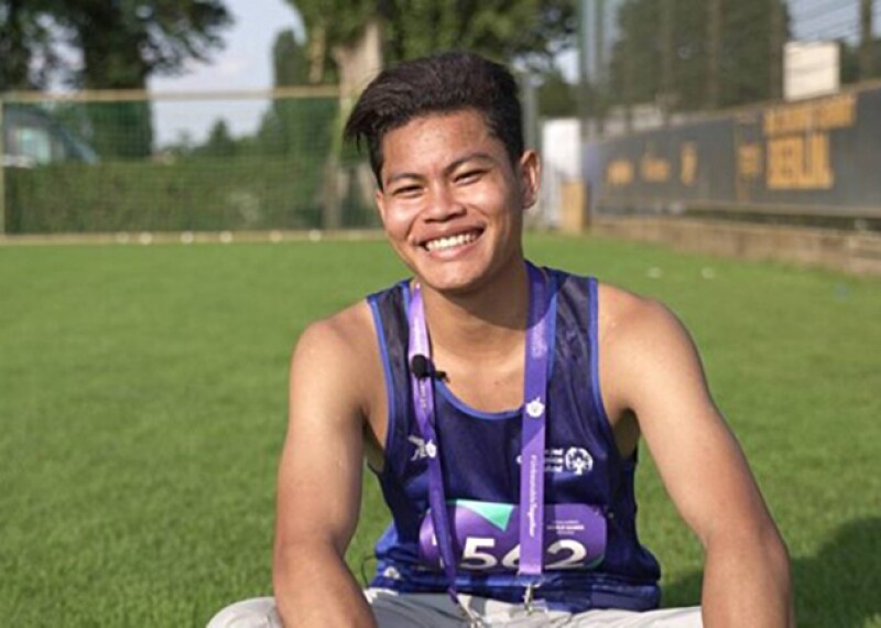 Young man sitting in a field on the grass. 