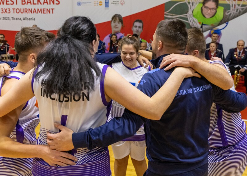 A team of 7 people wearing blue jerseys hugging and jumping