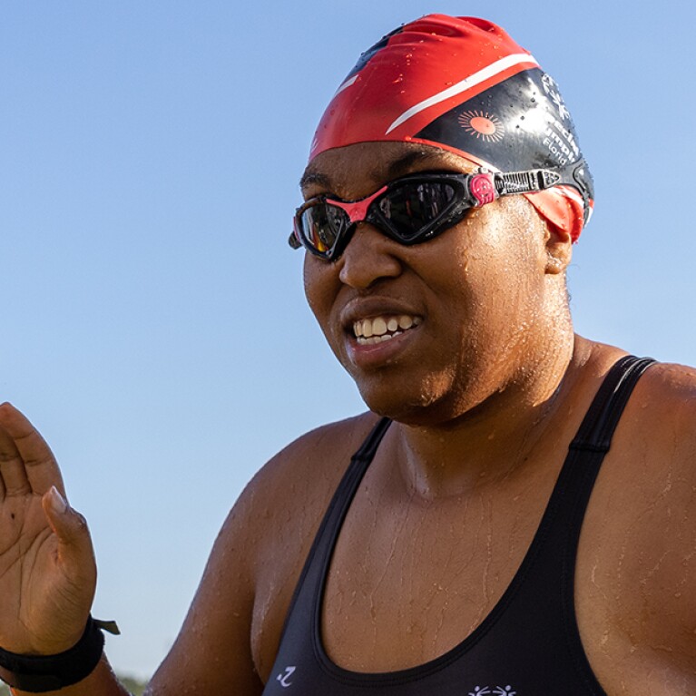 Swimmer waving as she gets out of the water. 