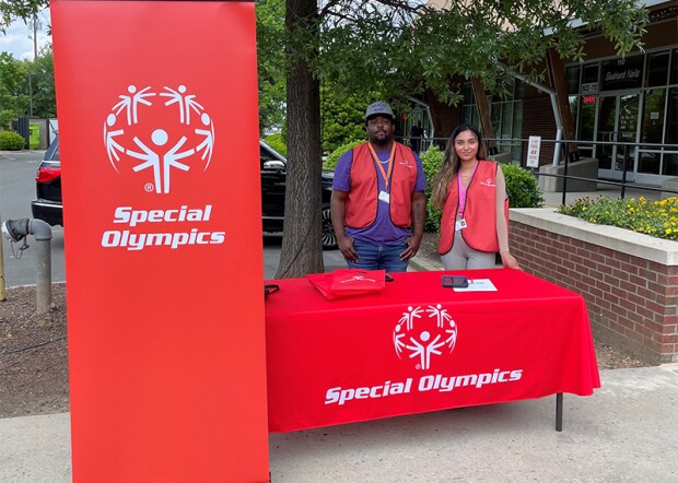 Two canvassers standing at a table with Special Olympics branding.