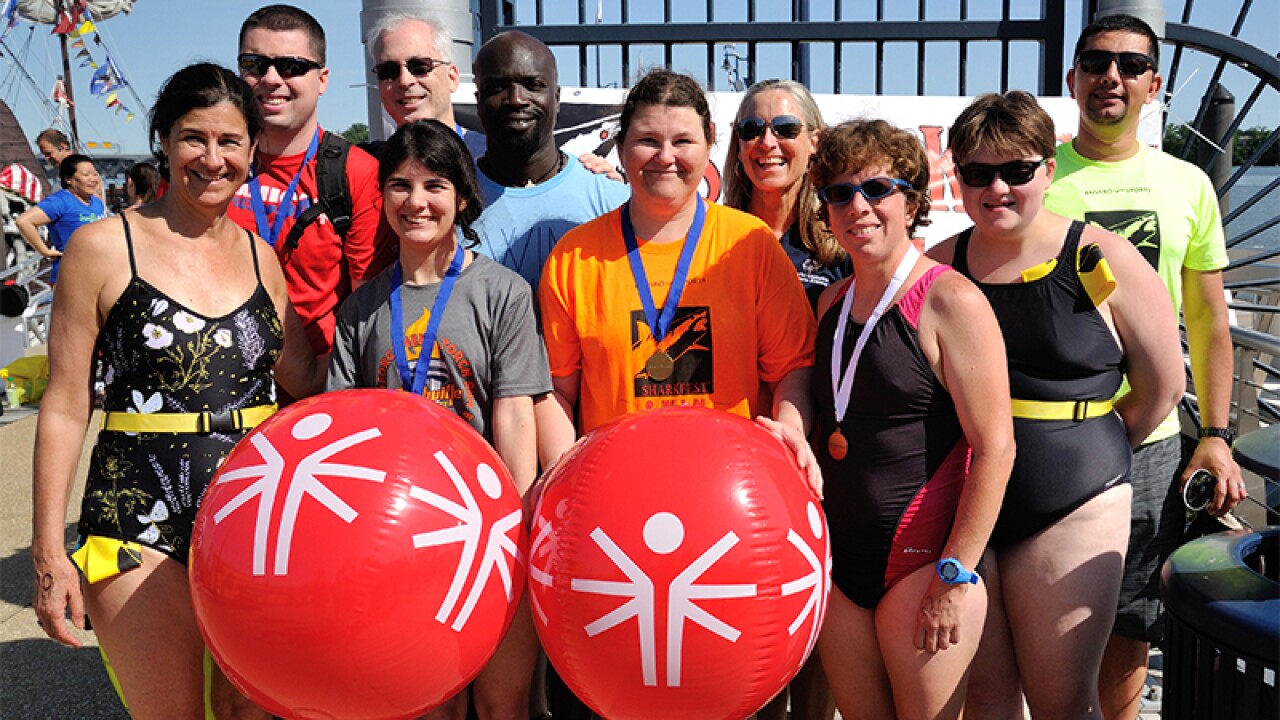 A group of athletes and participants including Kester Edwards stand together for a group photo. 