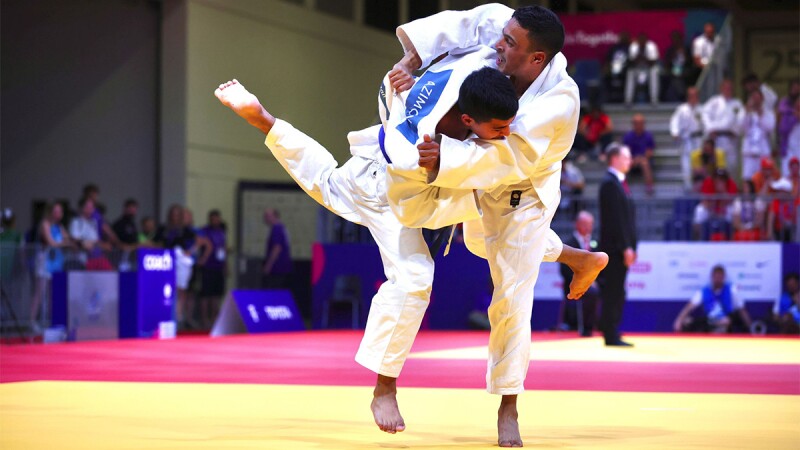 Two athletes engage on the mats at a judo competition. 