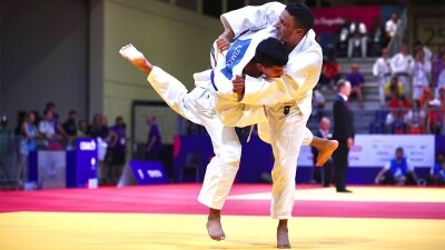 Two athletes engage on the mats at a judo competition. 