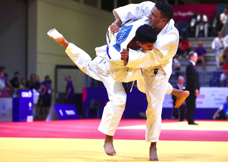 Two athletes engage on the mats at a judo competition. 