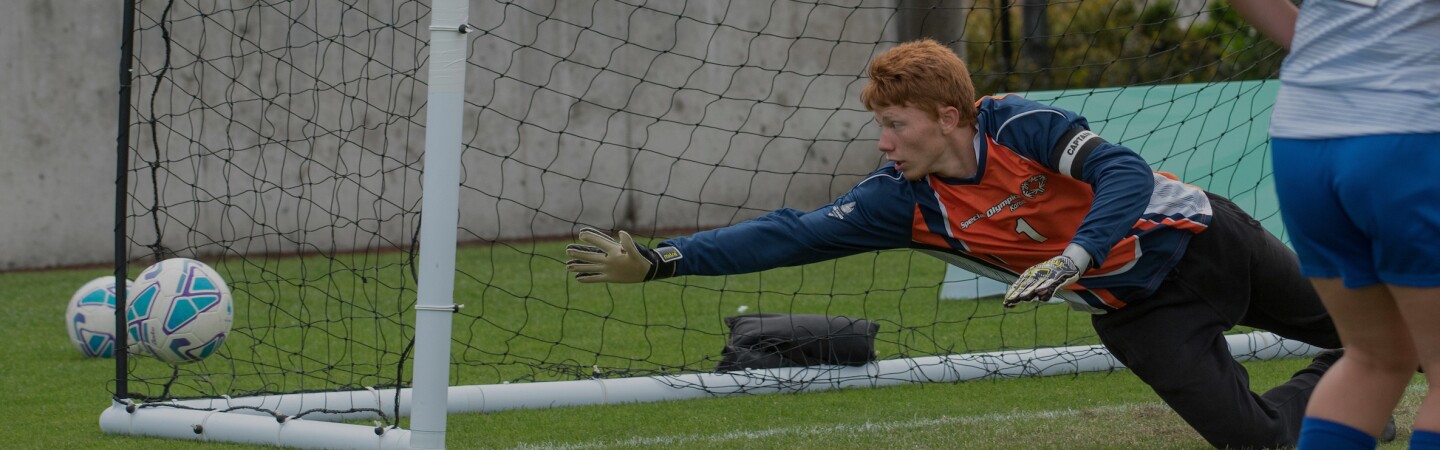 keeper diving for the ball before it makes it into the net. 