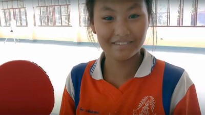 Chutipa smiling and holding a table tennis paddle. 