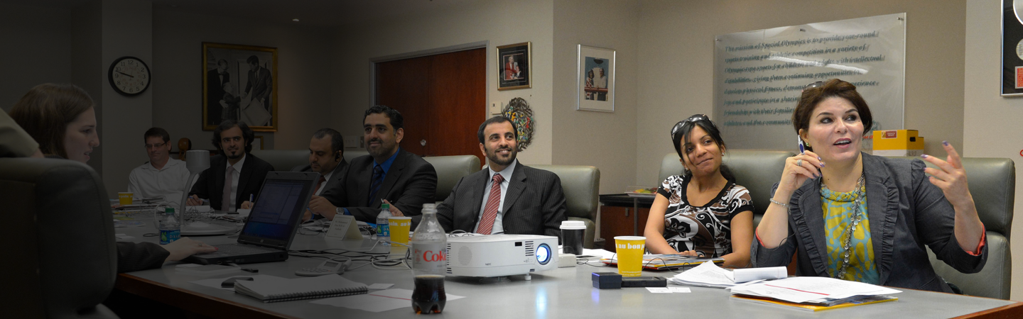 Group of people sitting around a table looking at a presentation. 