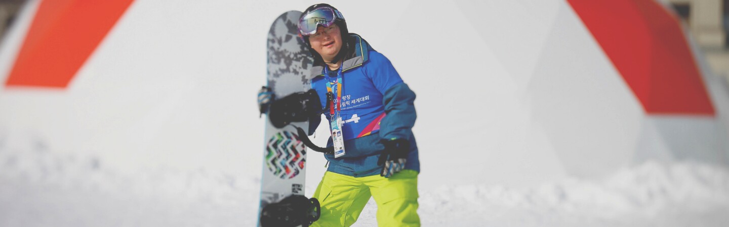 Athlete on the snow holding his board. 