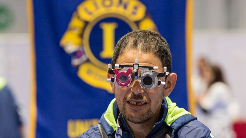 A young man with an ocular apparatus over his eyes sitting for an eye exam. 