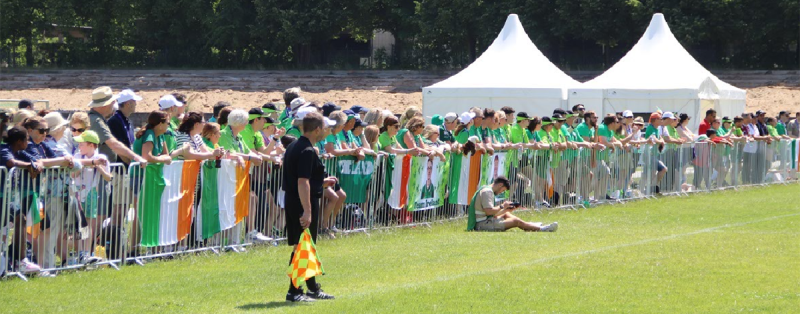 People standing along a fence with signs and flags