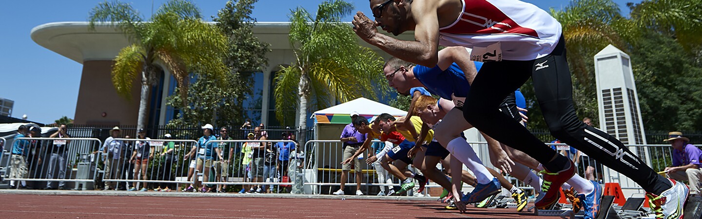 Male athletes taking their mark and start off running on the track. 