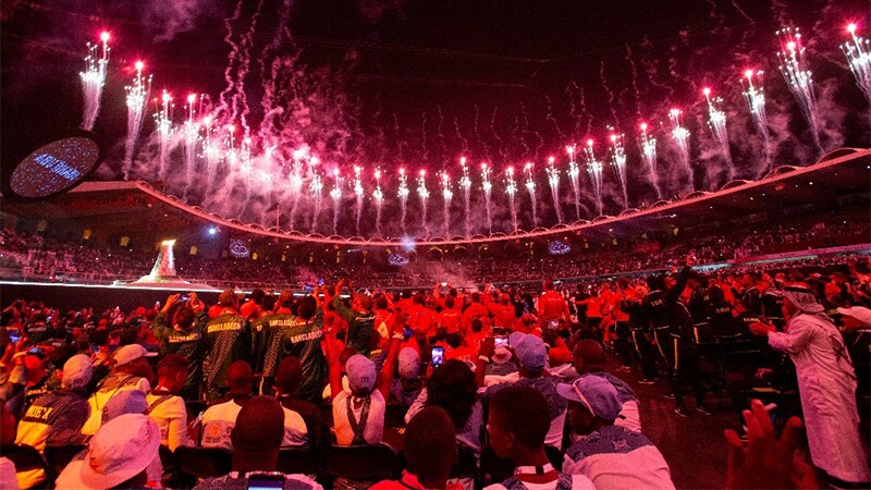 Fireworks going off at a stadium as a large crowd watches. 