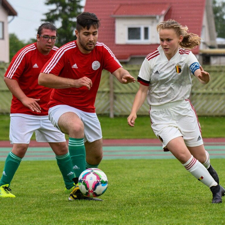 Two male and one female footballers on the field playing. 