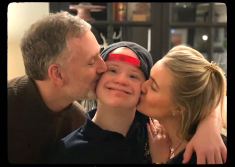 Mother and father kissing their son on the cheeks. 