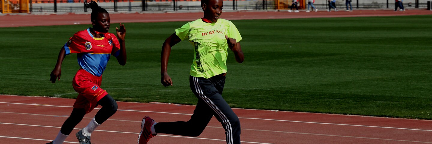 Two female athletes running on a track. 