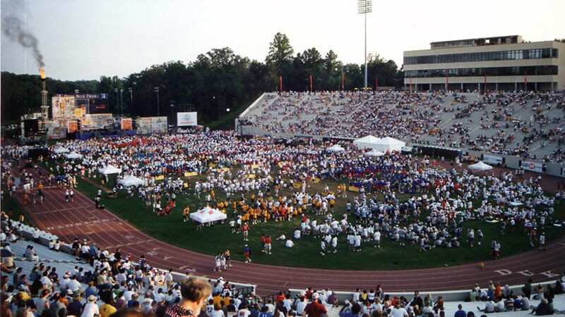 A field and bleachers full of people at the closing ceremony. 