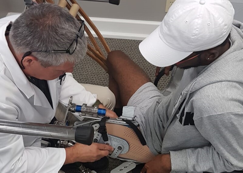 Dionte Foster sitting in a char on the right getting fitted with his athletic prosthetic. 