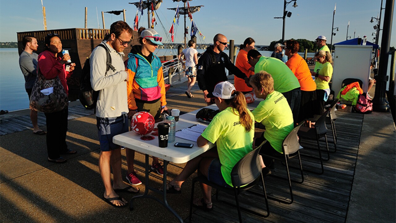 Attendees registering for the event at a table with volunteers on the dock. 