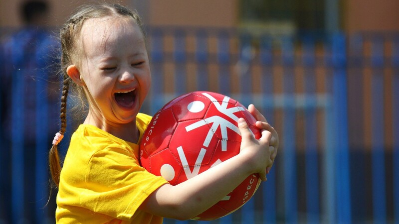 Special Olympics young female athlete smiling while holding a football.