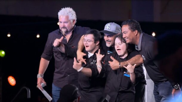 Guy Fieri on stage with athletes. 