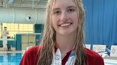 Young woman standing by the pool with medals around her neck. 