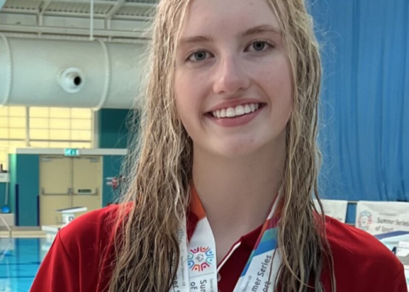 Young woman standing by the pool with medals around her neck. 