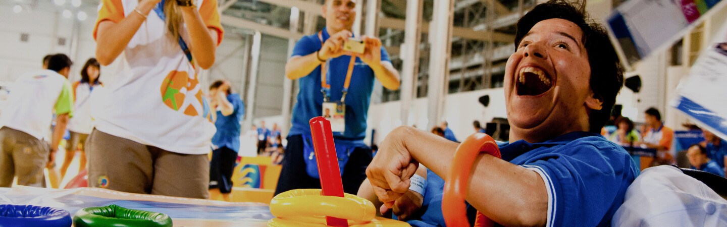 Athlete works with rings as as a coach cheers him on. 