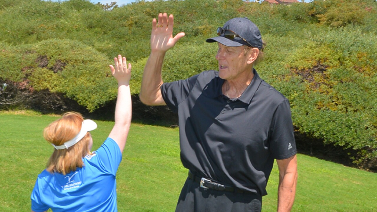 Young woman high fives older man on the golf green. 