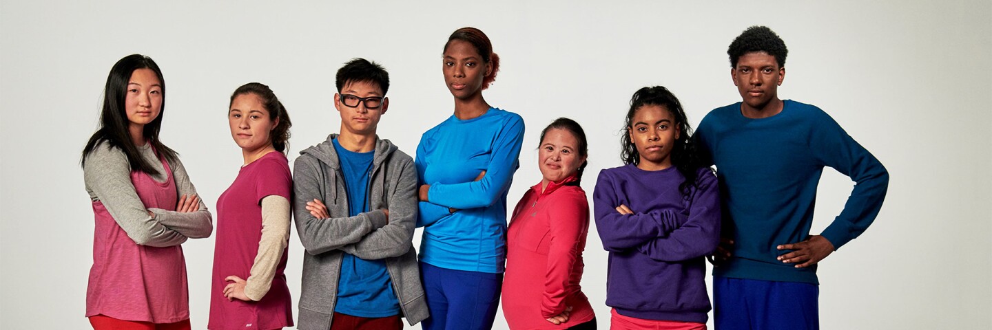 Group of seven young adults standing side by side for a group photo. 