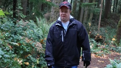 Special Olympics Washington athlete Reid Zimmer walking on a path through the woods.