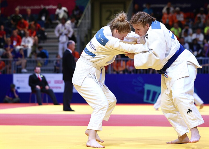 Two judo athletes with their arms entwined during match.