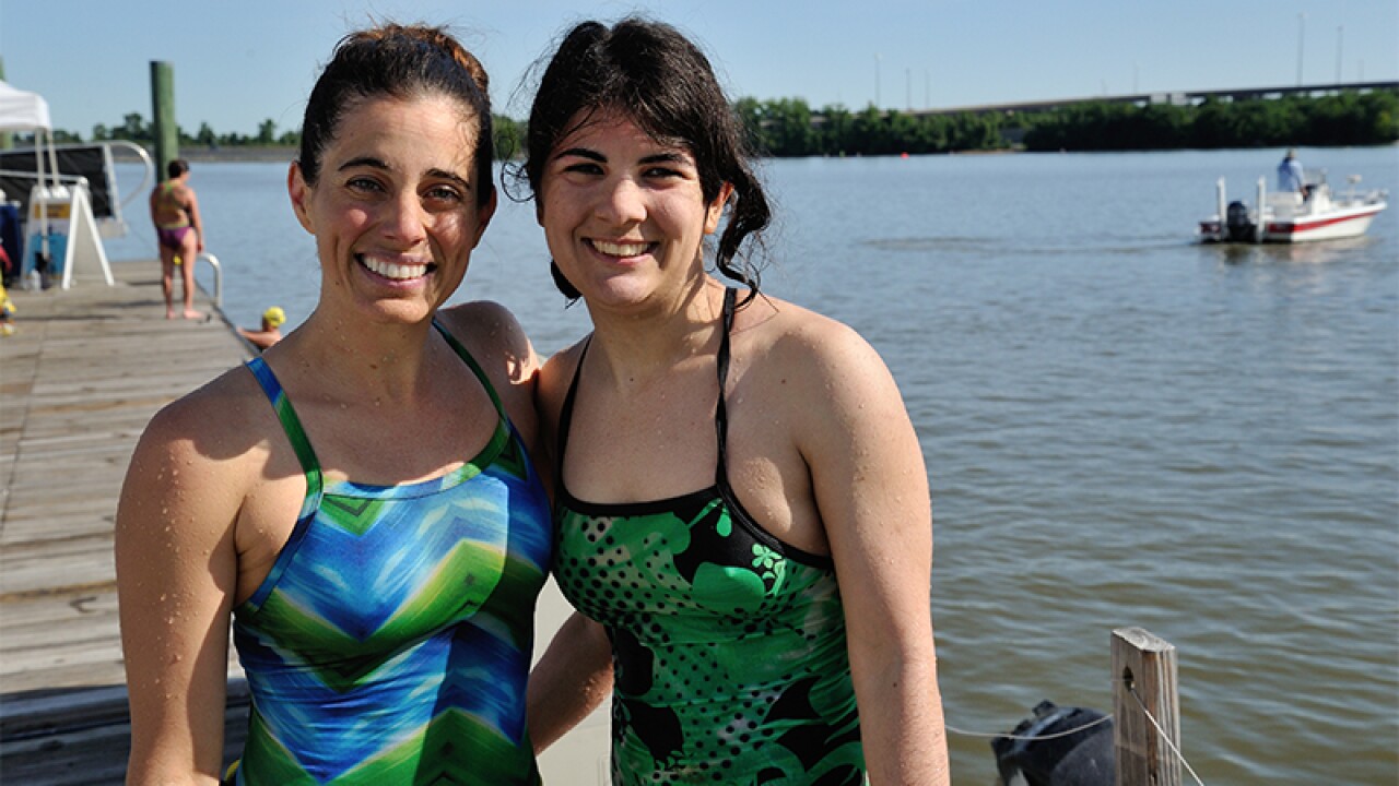 Two women on the docks, still wet after getting out of the water, poser for a photo together. 