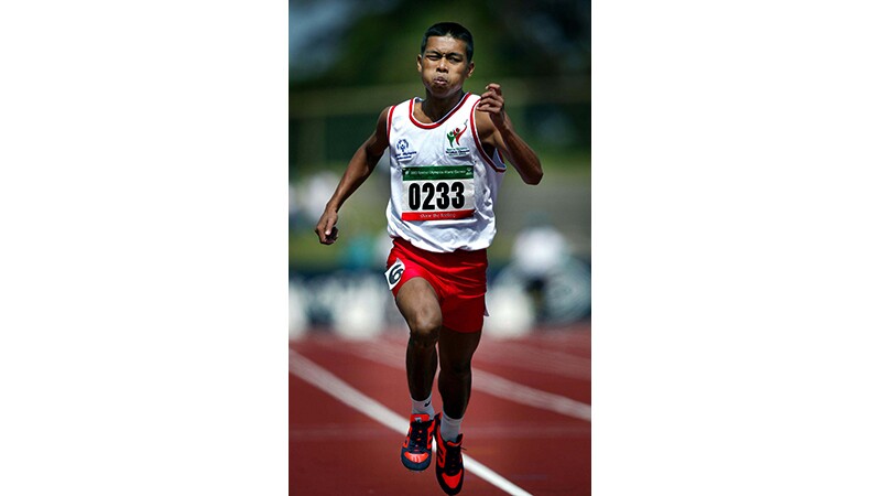 A runner running on the track at the 2003 World Games for the 100 Meter run.