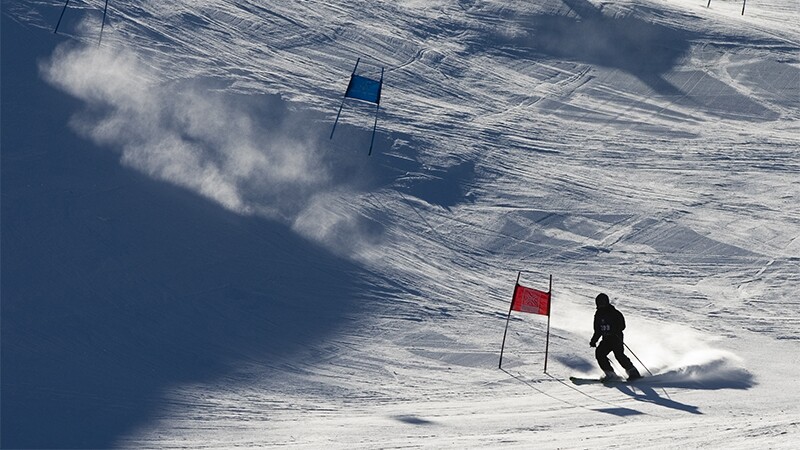 Skier going down the slope preparing to pass a flag. 