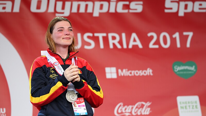 An athlete crying tears of joy with her medal draped around her neck. 