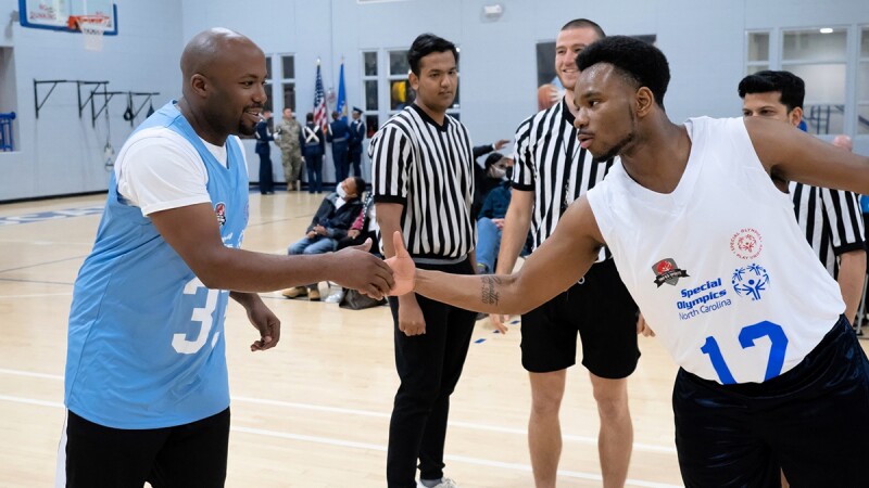 Two basketball players shake hands on the court. 