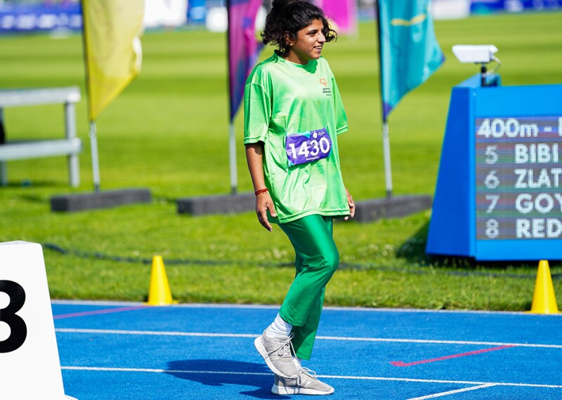 Sana, standing in lane 3, smiles and lifts her leg to move into starting position.