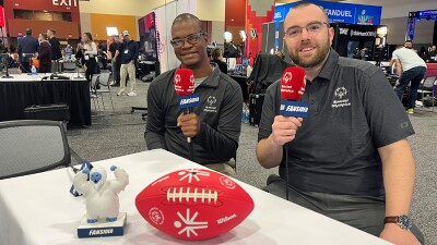 Two athletes sitting next to one another holding microphones. 