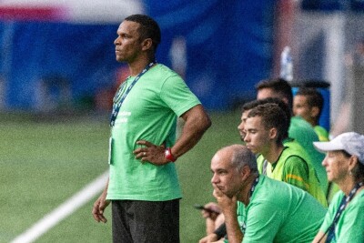 Man in green shirt standing with others sitting on a bench