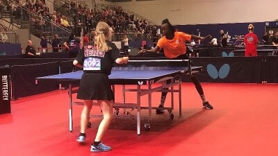 Two athletes playing a game of Table Tennis. 