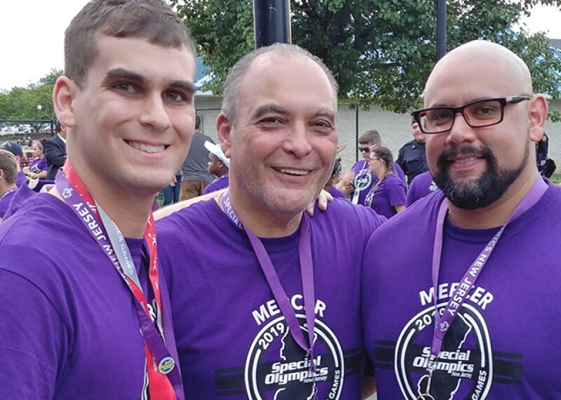 Coach Robert with his two sons Roberto Jr. and Coach Carlos; all three men wearing a MERCER 2019 Special Olympics New Jersey Games shirt. 