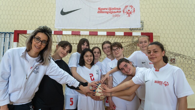 Group of girls and coach with all hands in standing in a circle. 