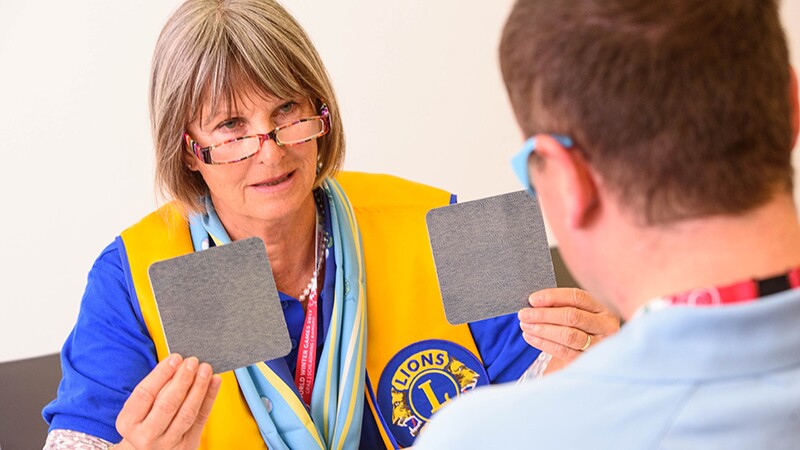 An athlete during an eye exam test while a volunteer assists him with the test. 