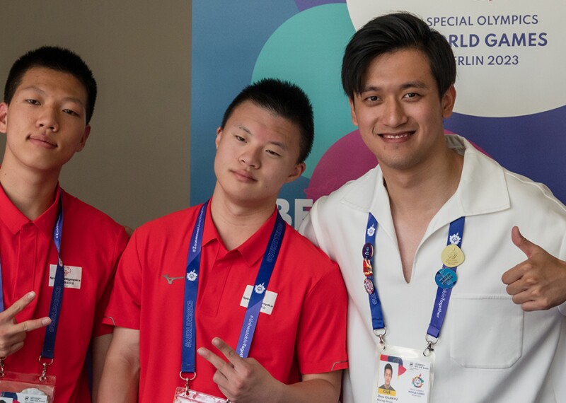 Medium close up shot of Zhou Guanyu posing with two athletes.