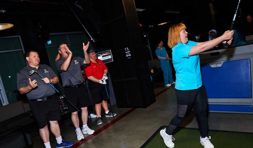 Woman hitting a ball with a golf club. 