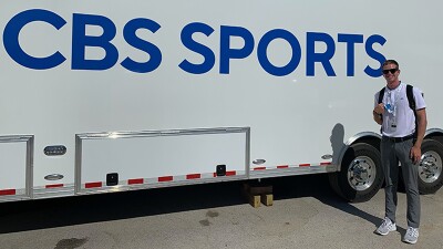 A man takes a picture outside a broadcast truck.